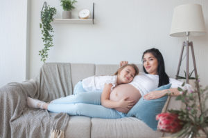 Schwangere Frau mit Kind uf der Couch